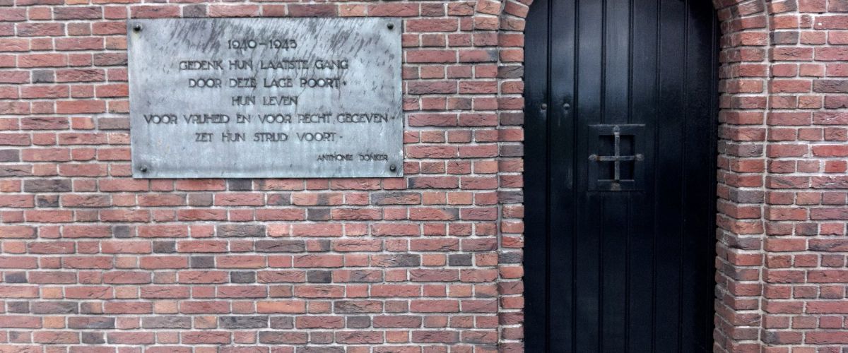 Muur Oranjehotel met gedenksteen en poortje